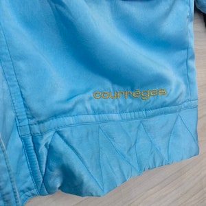 May include: A light blue jacket with a gold embroidered "courr&egrave;ges" logo on the bottom.