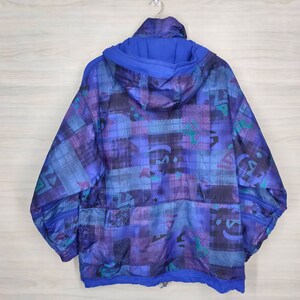 Puede incluir: Una chaqueta azul con capucha con un patr&oacute;n geom&eacute;trico en tonos de azul, morado y verde. La chaqueta tiene una cremallera y una capucha con cord&oacute;n.