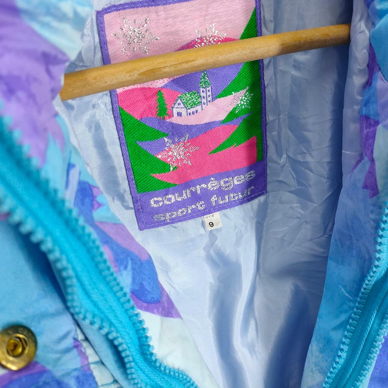 May include: A blue and purple ski jacket with a white, pink, and green logo that says "Courr&egrave;ges Sport Futur" and a size tag that says "9".