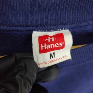Pode incluir: Uma etiqueta branca com texto vermelho que diz "Hanes" e "M" para o tamanho. A etiqueta tamb&eacute;m diz "North Carolina U.S.A."