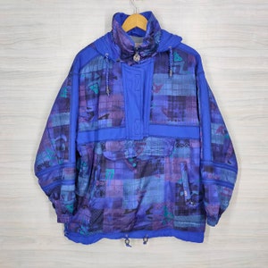 Puede incluir: Una chaqueta con capucha azul y morada con estampado, cierre de cremallera y cord&oacute;n en la parte inferior.