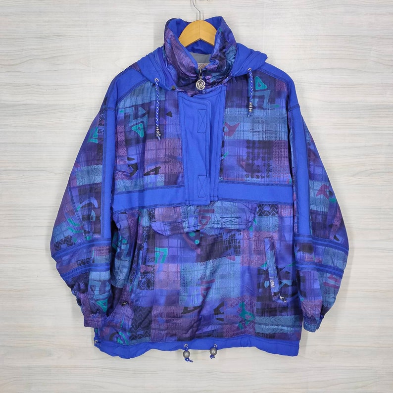Puede incluir: Una chaqueta con capucha azul y morada con estampado, cierre de cremallera y cord&oacute;n en la parte inferior.