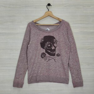 May include: A long-sleeved, maroon sweatshirt with a black skull and flower graphic. The skull has a floral design in its eye sockets.