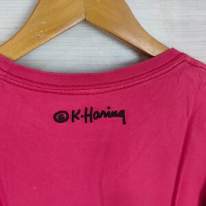 May include: A pink t-shirt with a black embroidered logo that says "&copy;K-Haring" on the back.