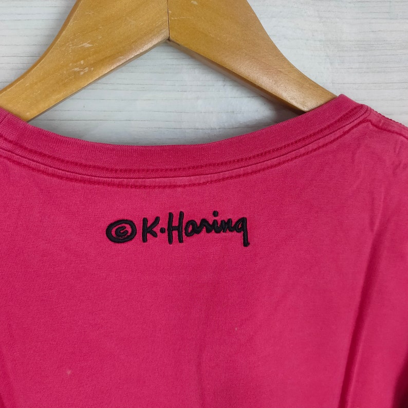 May include: A pink t-shirt with a black embroidered logo that says "&copy;K-Haring" on the back.