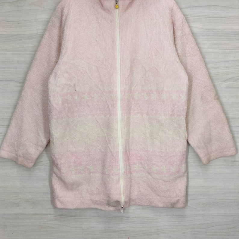 May include: A pink fleece jacket with a white zipper and a subtle white and pink pattern.