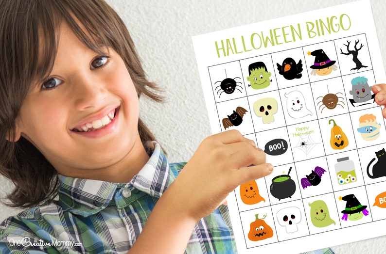 Similing boy holding up a Halloween bingo card.