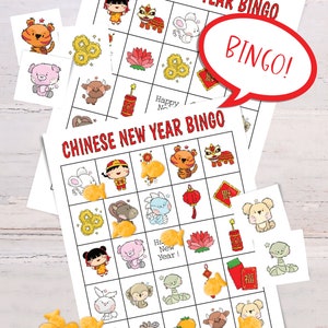 2 Chinese New Year bingo cards lying on a white table. Six calling cards are scattered across the game, and several spots are marked with goldfish crackers. A word bubble says Bingo!