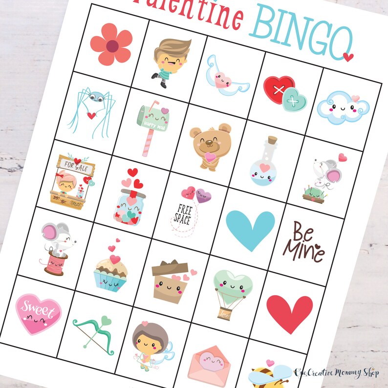 Zoomed in view of a cute Valentines Day bingo card lying on top of a white wooden table. Images on the card include flowers, hearts, cupid, a cute mouse, a mailbox, etc.