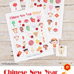 Two Chinese New Year bingo cards spread across a wooden tabletop. Red M and M candies are used as markers for the game.
