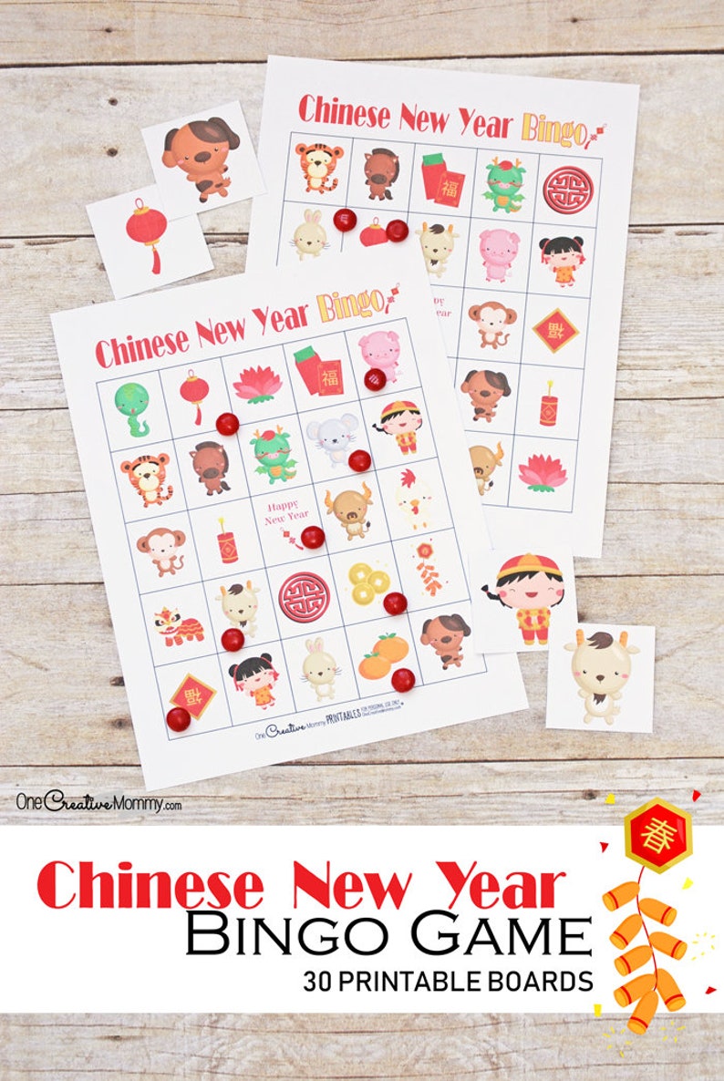 Two Chinese New Year bingo cards spread across a wooden tabletop. Red M and M candies are used as markers for the game.