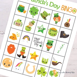 Zoomed in view of a St. Patricks Day bingo card laying on top of a white wooden table. Pictures include shamrock, balloons, leprechaun, four-leaf clover, pot of gold, rainbow, lucky horseshoe, and more.