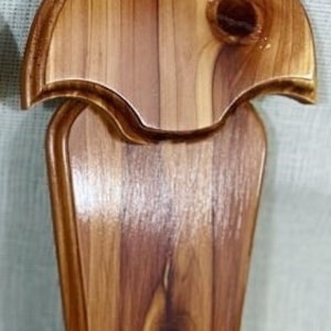 May include: Red Cedar Antler Mount. A wooden antler mount made of red cedar wood. The mount has a natural wood finish and a simple design.