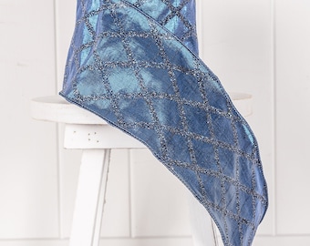 May include: A roll of shimmering blue ribbon with a diamond pattern. The ribbon has a metallic sheen and is decorated with silver glitter accents. The ribbon is displayed on a white stool, suggesting its use for crafts or gift wrapping.