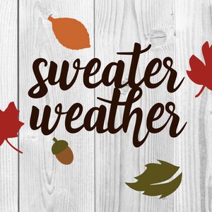 May include: A white wood background with the text "sweater weather" in brown cursive lettering. There are four fall-themed cutouts: a red maple leaf, a brown acorn, a green leaf, and an orange leaf.