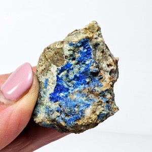 May include: A rough, irregular shaped rock with a blue and green mineral deposit. The rock is mostly brown and white with patches of blue and green.