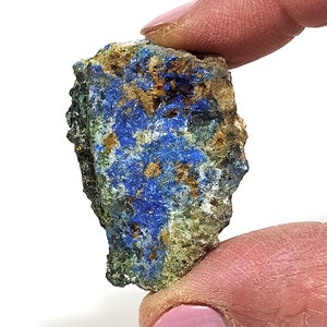 May include: A rough, irregular shaped piece of blue, green, and gold azurite mineral. The azurite has a rough, uneven surface and is a natural stone.