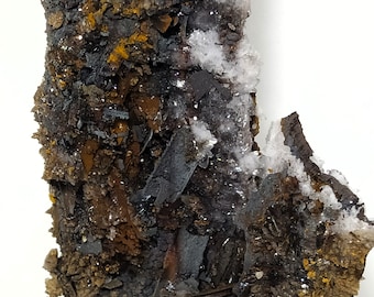 Puede incluir: Primer plano de una formación rocosa rugosa y texturizada con una mezcla de colores marrones, negros y blancos. La roca tiene un aspecto estratificado con cristales incrustados.