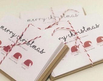 May include: A stack of white Christmas cards tied with red and white twine. The cards feature the text "merry christmas" and the names "Debs, Bella-Rose, Duke".