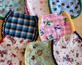 May include: Eight handmade baby bibs with different colorful patterns and crocheted trim. The bibs feature designs such as trains, butterflies, animals, and plaid.