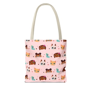 Op de afbeelding: Een roze tote bag met een herhalend patroon van cartoon katten en honden met harten en bloemen. De tas heeft crèmekleurige handvatten.