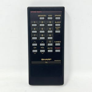 May include: A black Sharp infrared remote control for a television. The device features a numeric keypad, channel and volume controls, and buttons labeled Memory, Add, Erase, Sleep, Sleep Call, Flashback, Mute, and Power. The model number G0520CESA is printed near the bottom.