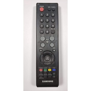 Può includere: Un telecomando per televisione rettangolare di colore nero con un tasto di accensione rosso nella parte superiore. Presenta un tastierino numerico, controlli per volume e canali, un anello di navigazione centrale con tasto invio e quattro tasti colorati.