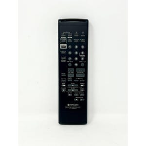 Puede incluir: Un mando a distancia Hitachi negro con numerosos botones para funciones de vídeo y TV. El mando tiene botones para encendido, volumen, canal y controles de reproducción. El número de modelo VT-351A es visible.