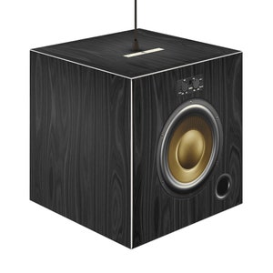 May include: A black, cube-shaped speaker with a wood grain effect and white edging. It features a gold-coloured speaker cone and a smaller port. Control knobs and a small plate are visible on top.