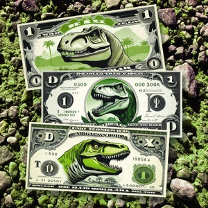 May include: Three novelty one-dollar bills featuring a green Tyrannosaurus Rex design. The bills have a green and white color scheme with the dinosaur's head prominently displayed. The bills are arranged on a bed of green and brown pebbles.