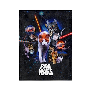 Könnte beinhalten: Eine schwarze Fleece-Decke mit einem Weltraum-Design, das mehrere Katzen in einer von Star Wars inspirierten Szene zeigt. Der Text "PAW WARS" ist in Weiß am unteren Rand der Decke aufgedruckt.