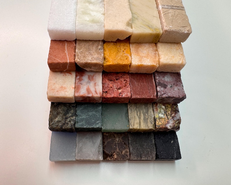 K&ouml;nnte beinhalten: Eine Sammlung kleiner, rechteckiger Steinproben in verschiedenen Farben und Texturen. Die Proben umfassen Farbt&ouml;ne von Wei&szlig;, Beige, Rot, Braun, Gelb, Gr&uuml;n und Schwarz. Jedes St&uuml;ck hat ein einzigartiges Muster und eine einzigartige Oberfl&auml;che.