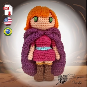 May include: Crocheted doll with orange hair, green eyes, a purple cape, a pink dress, and brown boots. The doll is standing on a brown and tan background. The text "Eu quero Croche" is visible in the lower right corner of the image.
