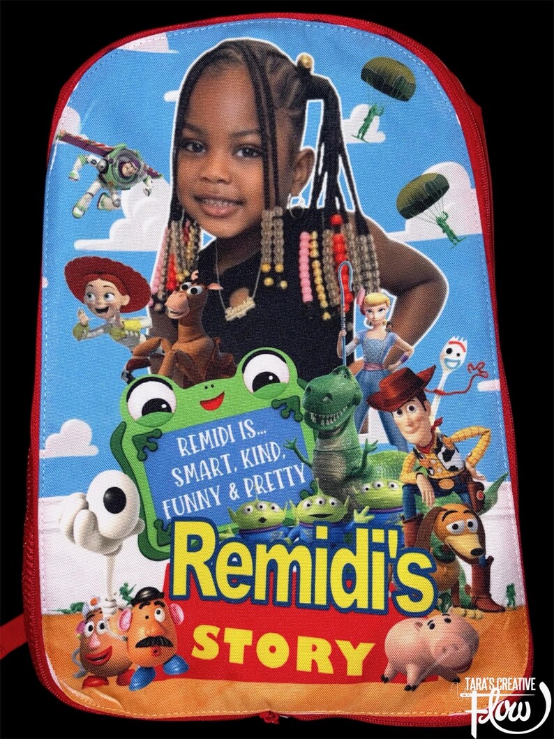 May include: A blue backpack featuring a photographic portrait of a young child with braided hair, surrounded by various animated characters. The text reads: REMIDI IS... SMART, KIND, FUNNY & PRETTY, Remidi's STORY. The bag has a red zipper border.