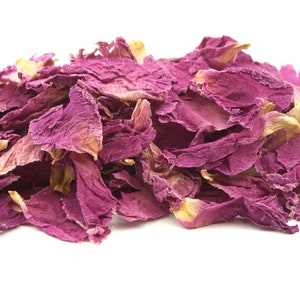 May include: A pile of dried rose petals in shades of pink and faded yellow against a white background. The petals have a delicate, textured appearance, suggesting they are for culinary or cosmetic use.