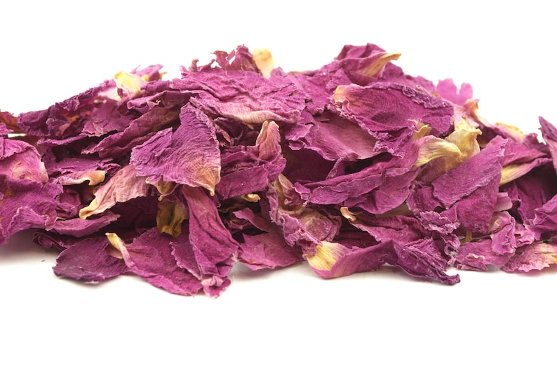 May include: A pile of dried rose petals in shades of pink and faded yellow against a white background. The petals have a delicate, textured appearance, suggesting they are for culinary or cosmetic use.