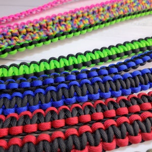 May include: A collection of paracord straps featuring intricate braided patterns. The straps are available in various color combinations including neon green and black, royal blue and black, red and black, and a multi-colored rainbow pattern.