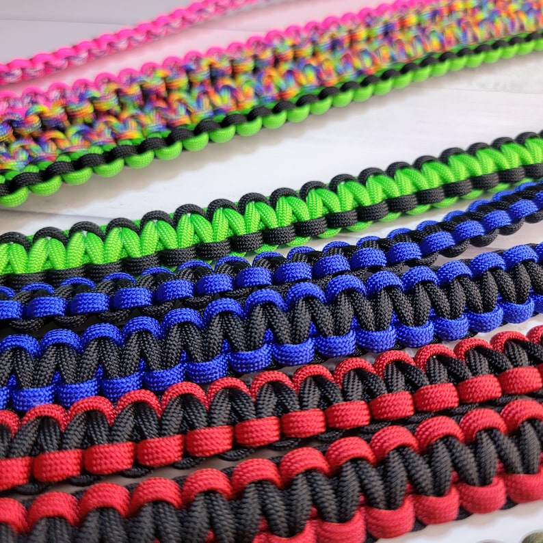 May include: A collection of paracord straps featuring intricate braided patterns. The straps are available in various color combinations including neon green and black, royal blue and black, red and black, and a multi-colored rainbow pattern.