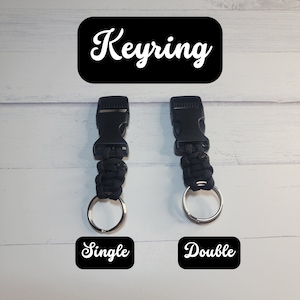 May include: Two black paracord keyrings with plastic side-release buckles and silver metal split rings. The left keyring is labeled Single and the right is labeled Double. The text Keyring appears at the top of the image in white font.
