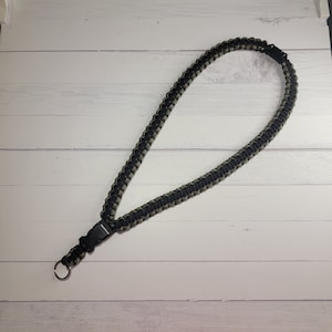 May include: A black and green paracord lanyard with a black plastic clip and a silver ring.