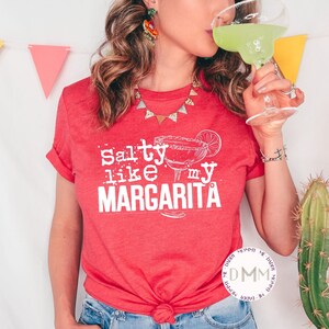 May include: A red t-shirt with the text "Salty like my Margarita" in white lettering. The shirt features a graphic of a margarita glass with a lime wedge.