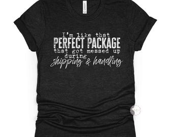 Może przedstawiać: Czarny melanżowy t-shirt z białym napisem: "I'm like that PERFECT PACKAGE that got messed up during shipping & handling". Koszulka ma dekolt w serek i krótkie rękawy.