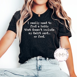 Necesito encontrar un pasatiempo que no incluya mi tarjeta de débito ni comida. Camiseta divertida, camiseta sarcástica, camiseta de humor para adultos, camiseta gráfica.