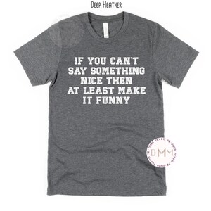May include: A dark heather grey t-shirt with the text "IF YOU CAN'T SAY SOMETHING NICE THEN AT LEAST MAKE IT FUNNY" printed in white.