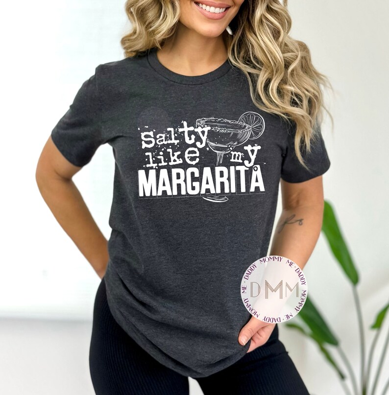 May include: A dark gray t-shirt with the text "Salty like my Margarita" in white. The text is accompanied by a drawing of a margarita glass with a lime wedge.