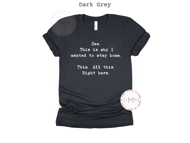 May include: Dark grey t-shirt with the text "See. This is why I wanted to stay home. This. All this. Right here." in white. The shirt has a crew neck and short sleeves.