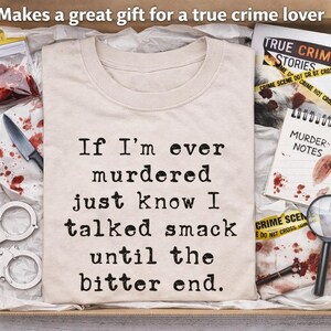 K&ouml;nnte beinhalten: Geschenkbox mit einem beigefarbenen T-Shirt mit dem Text "If I'm ever murdered just know I talked smack until the bitter end." Die Box enth&auml;lt auch Handschellen, ein Messer und einen Notizblock mit "Murder Notes."