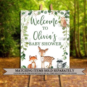 May include: Welcome to Olivia's Baby Shower sign with a green leafy border and woodland animal illustrations. The sign features a fox, a deer, a raccoon, and an owl.