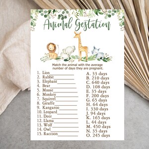 Könnte beinhalten: Eine druckbare Spielkarte mit einem grün-braunen Farbschema. Die Karte trägt den Titel "Animal Gestation" und eine Liste von Tieren mit ihren durchschnittlichen Tragzeiten. Die Karte ist mit Illustrationen von Tieren verziert, darunter ein Löwe, ein Kaninchen, ein Elefant, ein Bär, ein Elch, ein Affe, ein Eichhörnchen, eine Giraffe, ein Känguru, ein Leopard, ein Reh, ein Lama, ein Wolf, eine Eule und ein Waschbär.