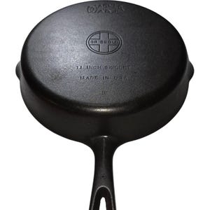 May include: A black cast iron skillet with a handle and a round cooking surface. The skillet is marked "11 INCH SKILLET" and "MADE IN USA". The brand name "GRISWOLD" is also visible.